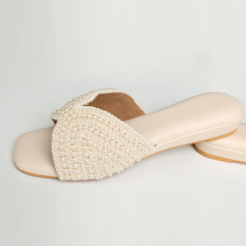 White all-over pearl embellished flat slide sandals on mannequin foot with cream fabric and dried flowers background – Riwaaz Noor-e-Moti collection