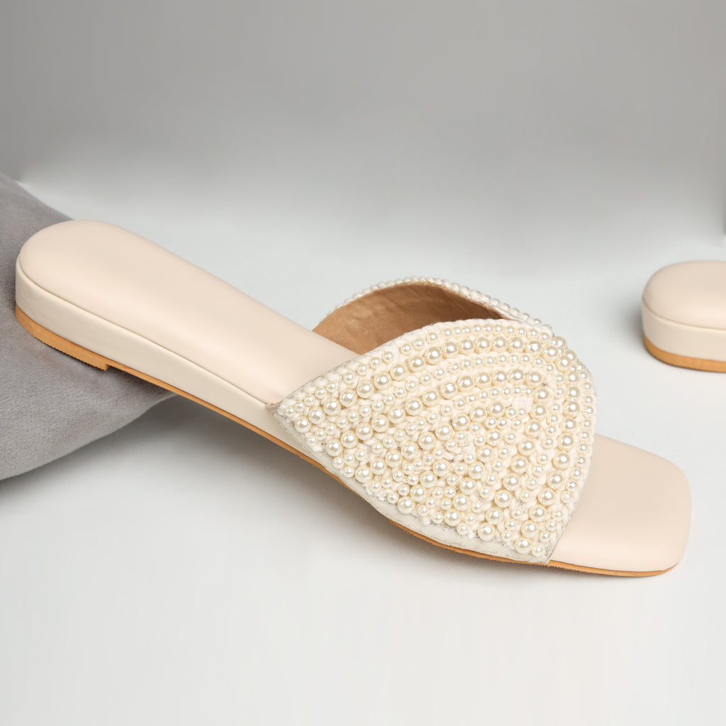 Model wearing Riwaaz Noor-e-Moti white pearl flat slides with white chikankari kurta on jute rug – close-up foot shot