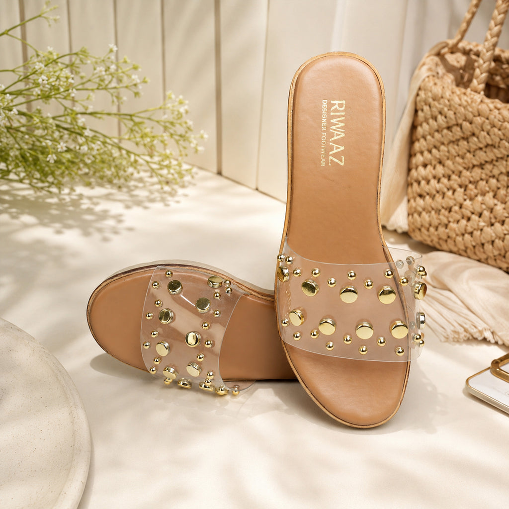 Model seated in white ethnic wear wearing Riwaaz Nora dark beige gold stud clear strap wedge slides – lifestyle shot
