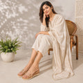 Pair of Riwaaz Nora dark beige clear strap gold stud wedge slides showing wood-effect platform sole and beige insole – bottom angle view