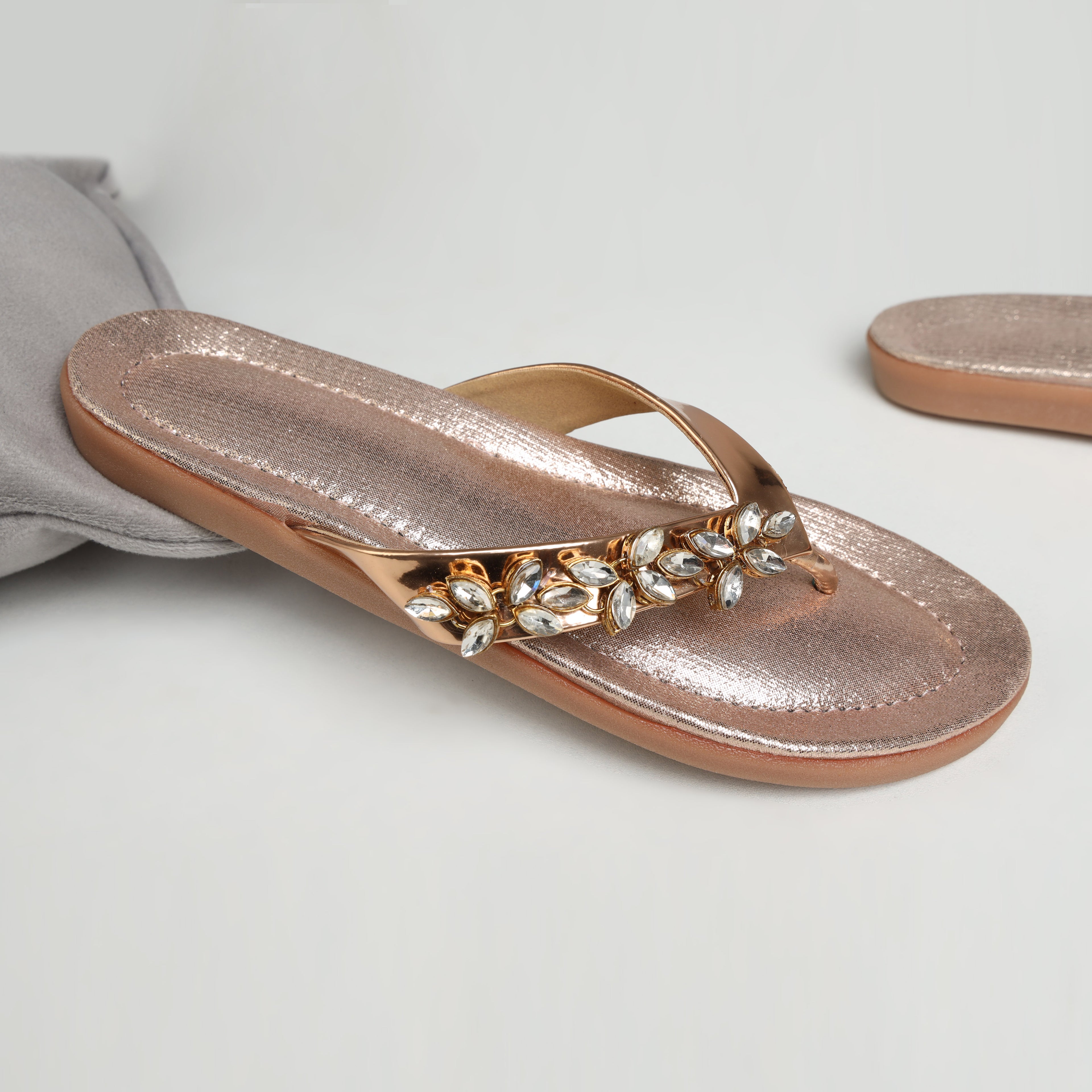 Model wearing Riwaaz Ziva dull rose gold Kundan embellished flip flops with pink embroidered salwar suit – close-up foot shot on jute rug