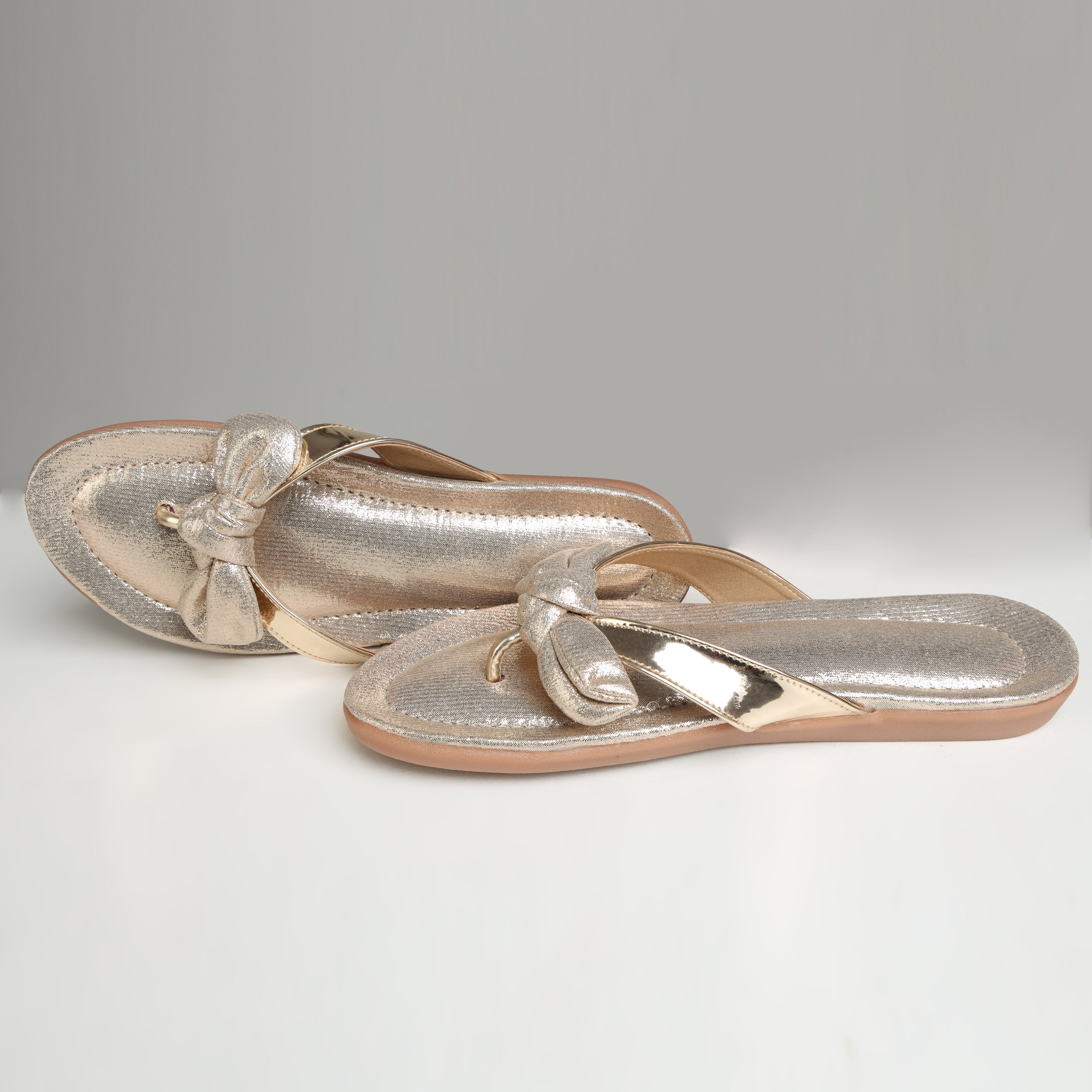 Pair of Riwaaz Misha dull rose gold mirror work flip flops – flat lay top view showing full shimmer footbed and bow detail