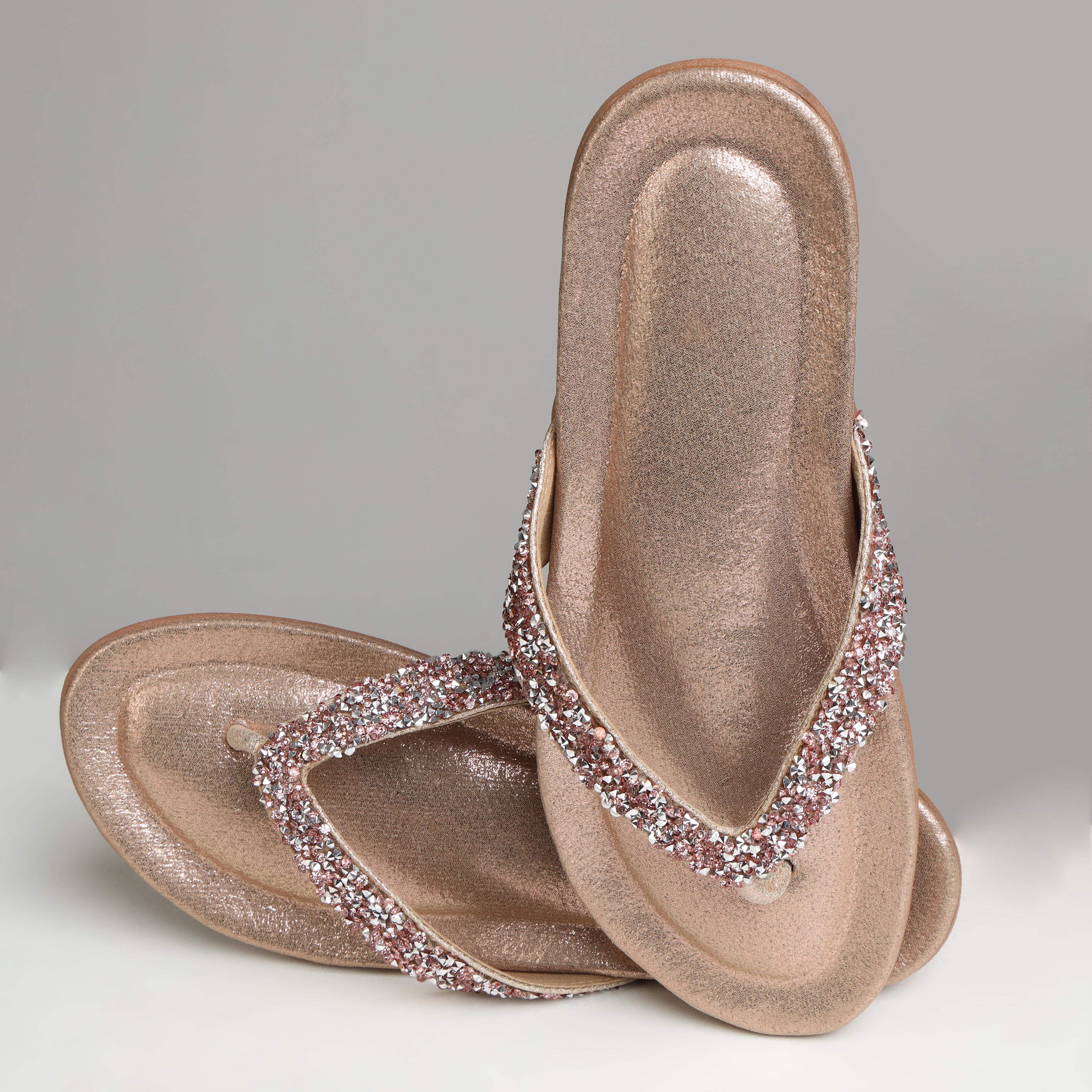 Pair of Riwaaz Aurelia dull rose gold crystal flip flops on white background – flat lay top view showing full crystal strap and rose gold footbed