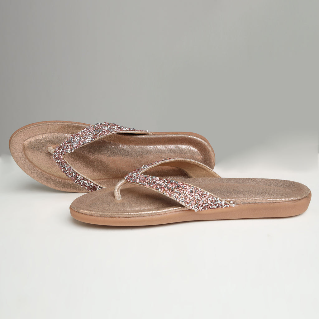 Pair of Riwaaz Aurelia dull rose gold crystal flip flops on white background – side angle showing cushioned sole profile and crystal strap detail