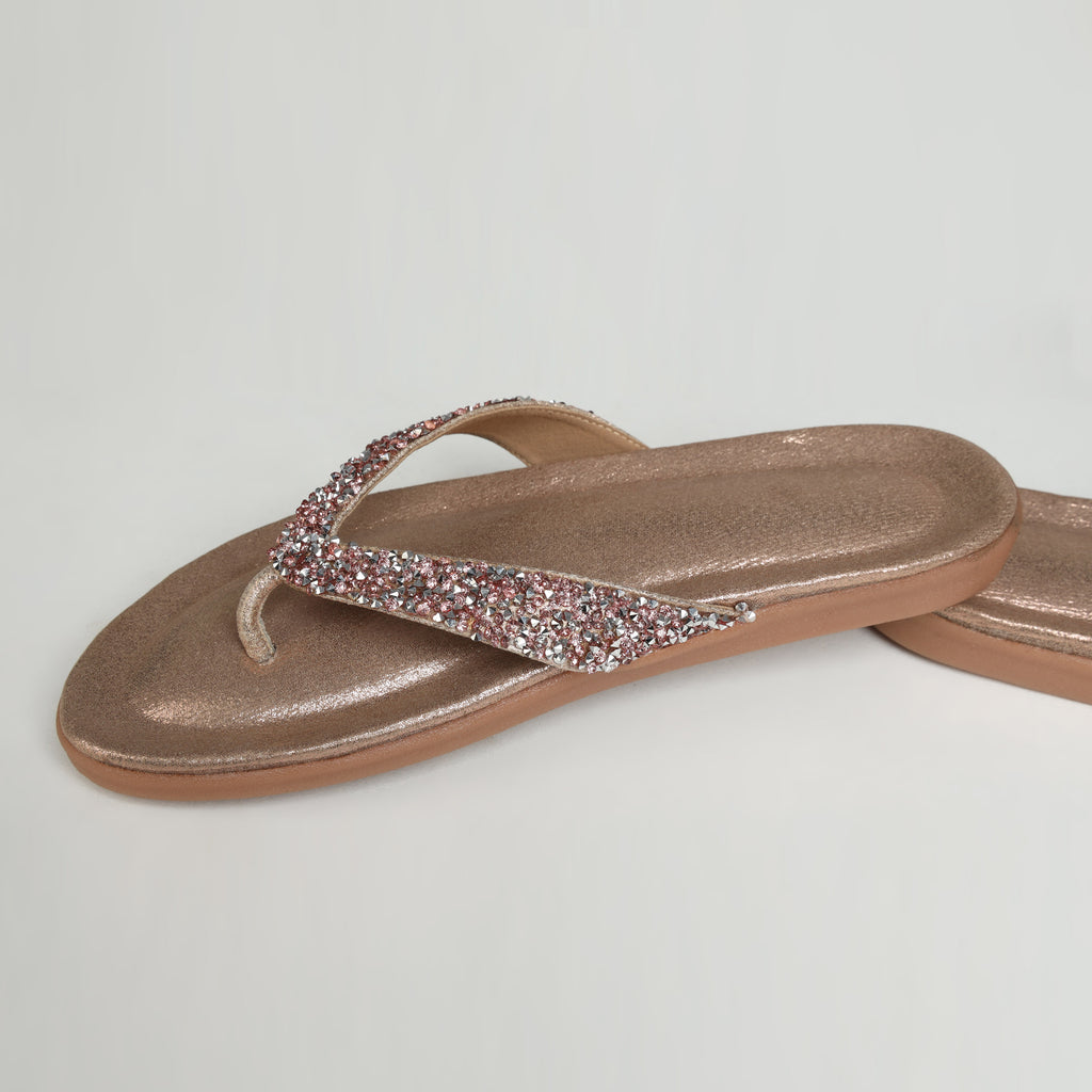 Pair of Riwaaz Aurelia dull rose gold crystal flip flops – overhead flat lay on white background showing shimmer insole and full crystal strap coverage