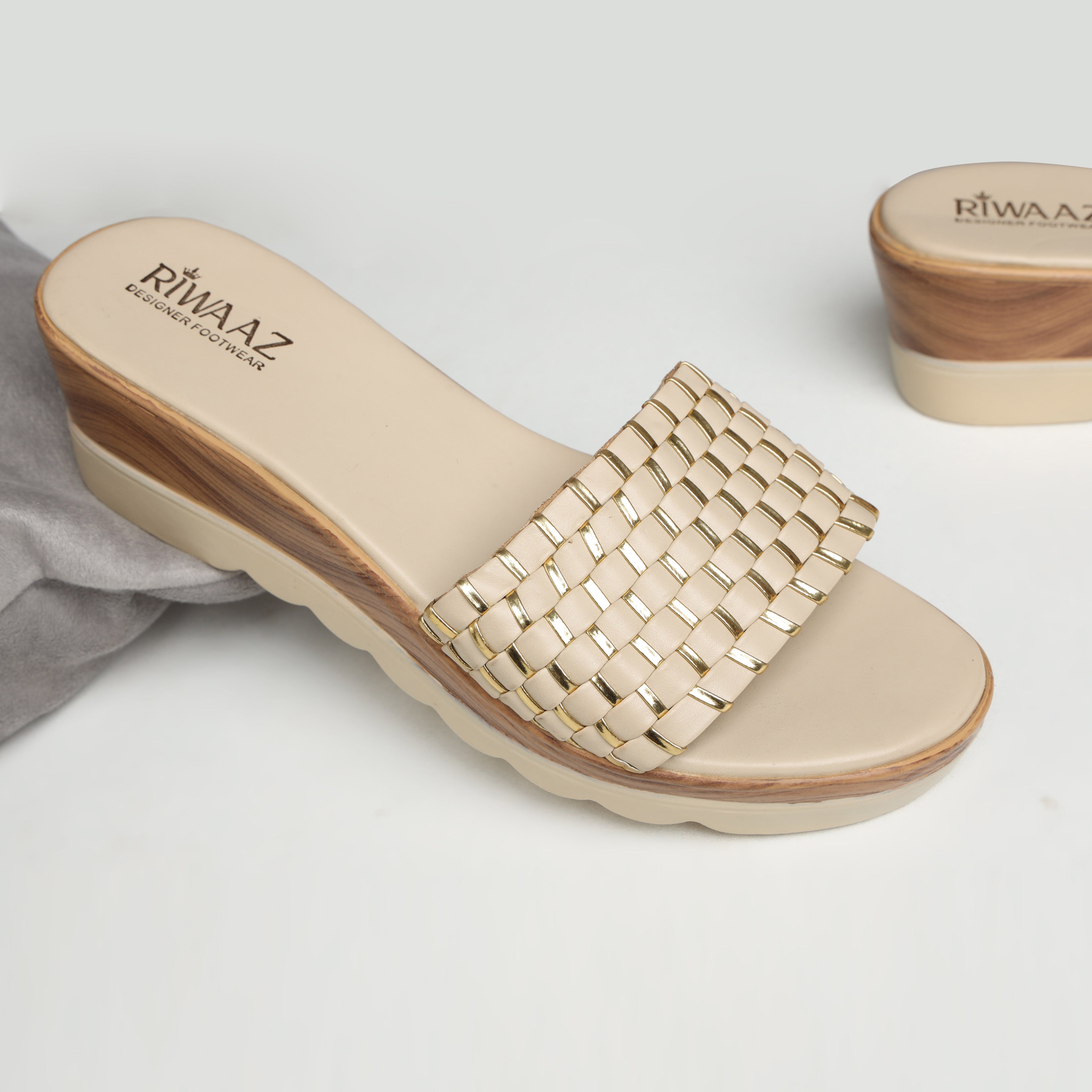 Model wearing Riwaaz Ava cream woven metallic accent platform slides with cream embroidered salwar – close-up foot shot on jute rug in warm Indian courtyard setting