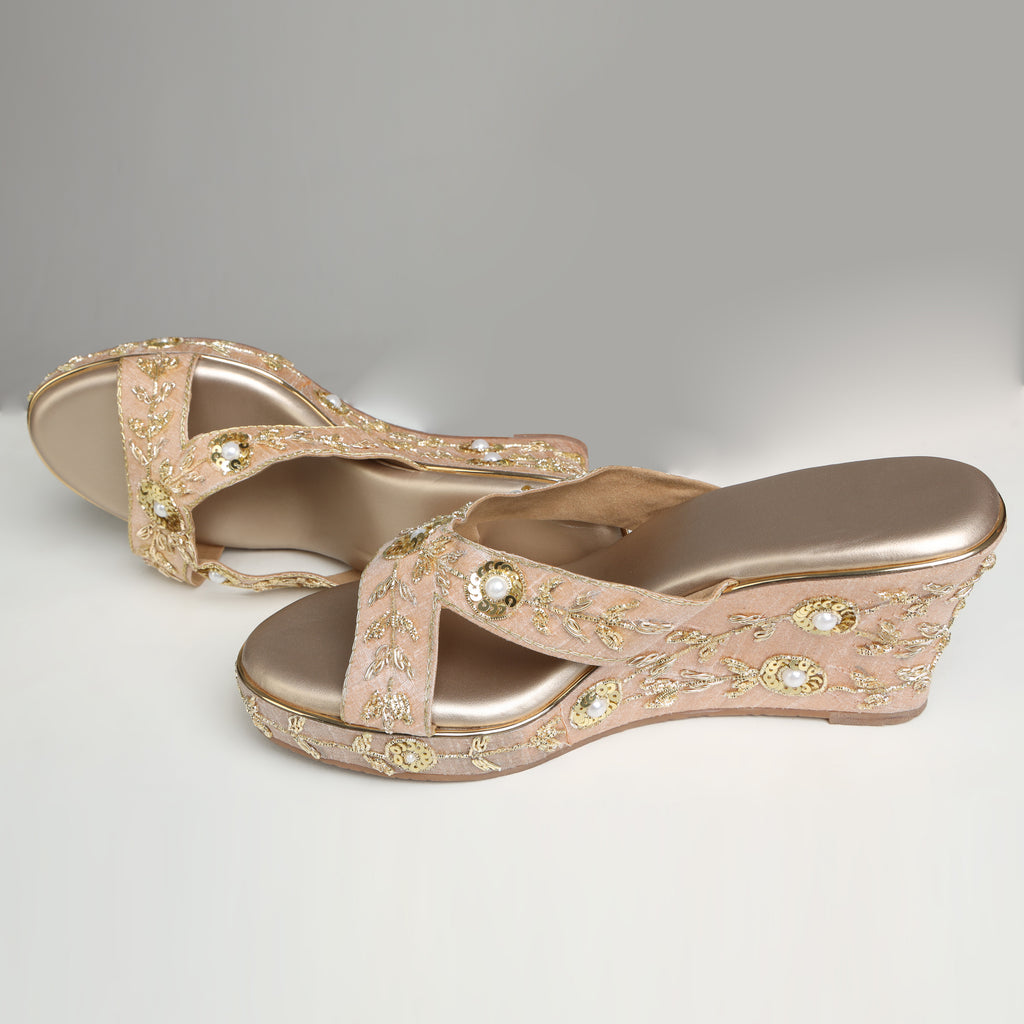 Pair of Riwaaz Noor rose gold zari embroidered bridal wedge heels on white background – angled view showing cushioned gold insole and fully embroidered wedge body with pearl accents