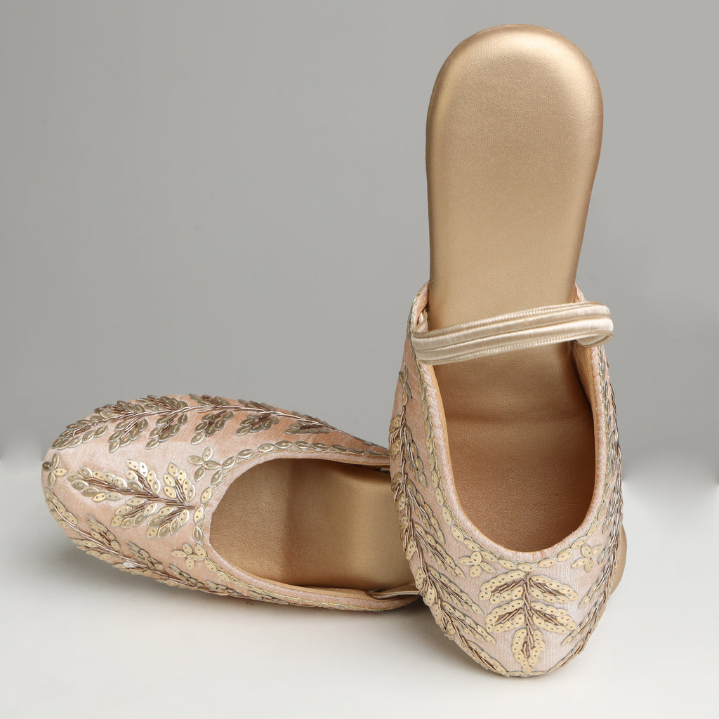 Pair of Riwaaz Zehra dull gold sequin leaf embroidered slingback wedge mules on white background – front angled view showing full sequin leaf embroidery coverage on blush base and gold wedge profile