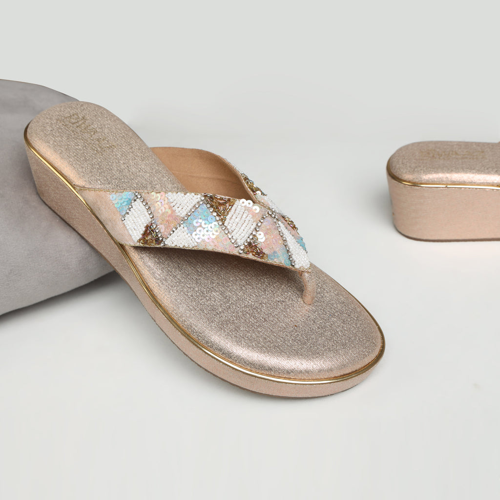Model wearing Riwaaz Afreen dull rose gold pastel geometric beaded thong wedge platforms with gold tissue kurta set – close-up foot shot on stone floor showing mint, blush and white diamond beadwork strap
