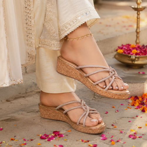 Pair of Riwaaz Zarina Glow dark beige crystal crossover cork wedge platforms on white background – angled top view showing full rhinestone-encrusted crossover strap pattern and gold-trimmed cork wedge
