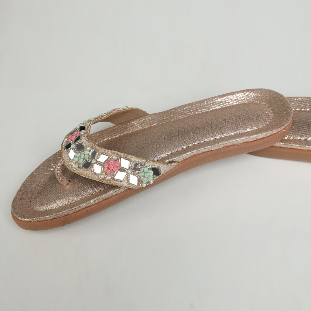 Riwaaz Misha dull rose gold mirror work flip flop – close-up angled shot showing mirror tile and pastel bead detail on strap with grey fabric in background