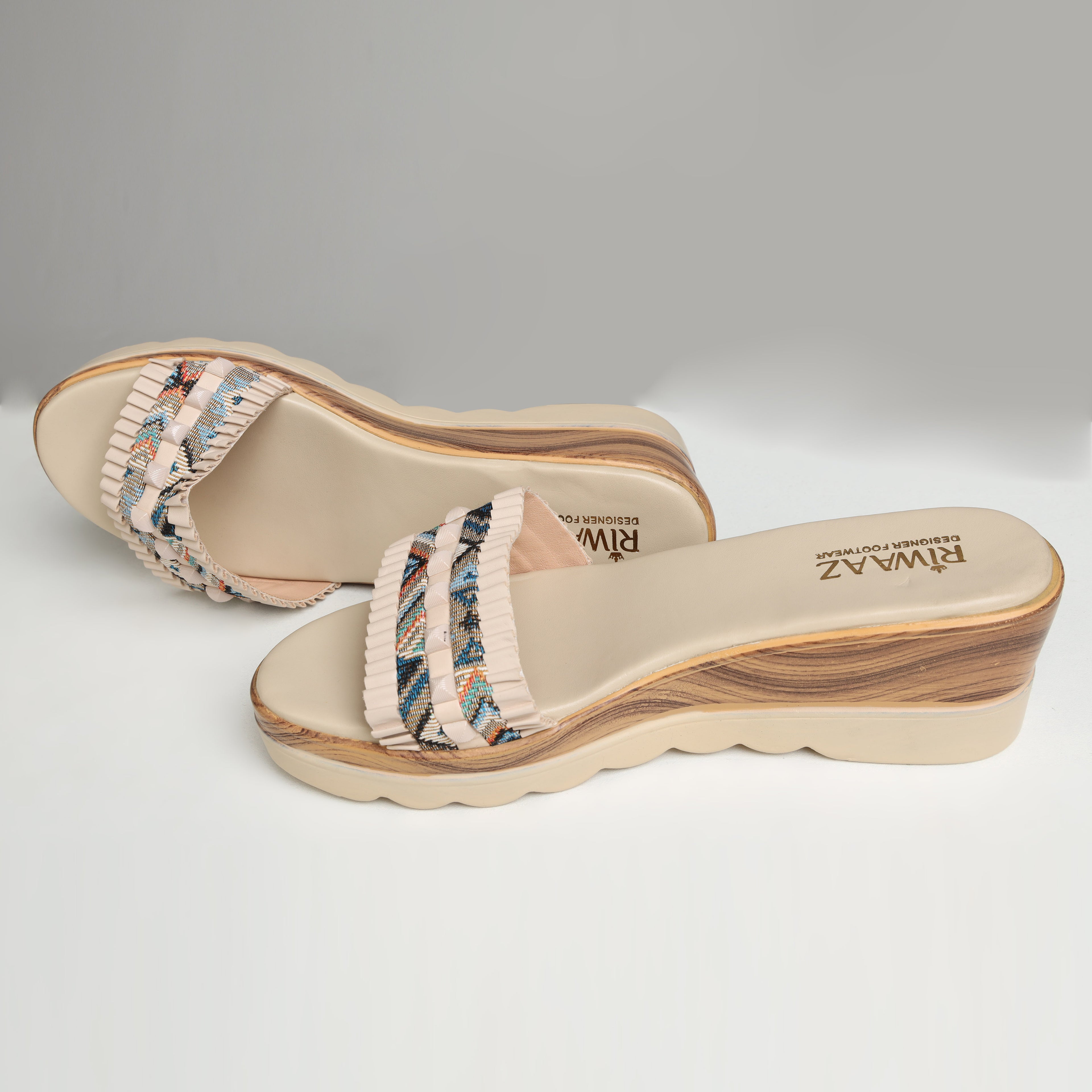Pair of Riwaaz Elara cream printed pleated strap wedge slides on white background – top-down product shot showing cream cushioned insole with Riwaaz branding and full multicolour geometric print pleated strap