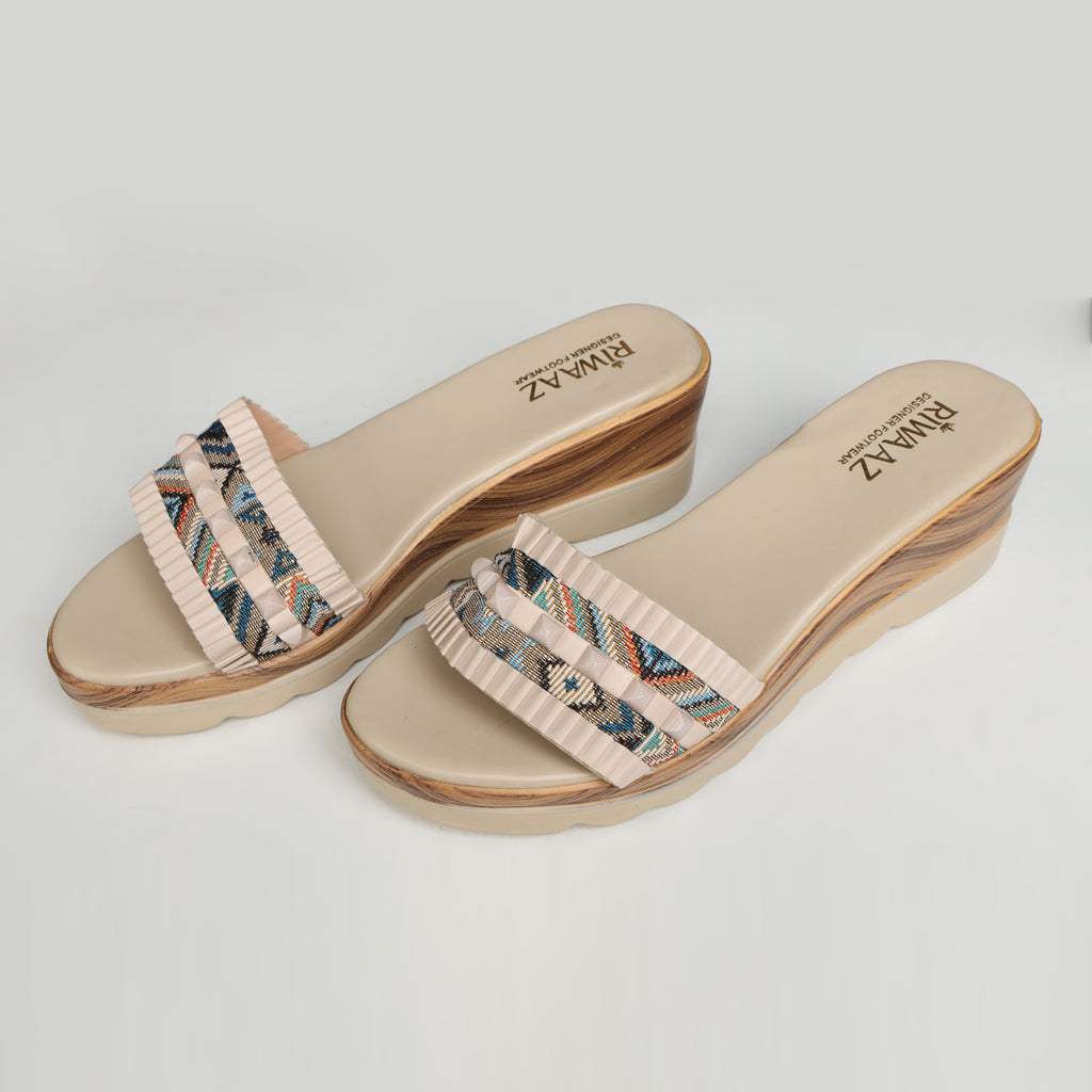 Single Riwaaz Elara cream printed pleated strap wedge slide – side profile product shot on white surface with grey fabric and Riwaaz box in background showing multicolour geometric print strap with cream pleated trim