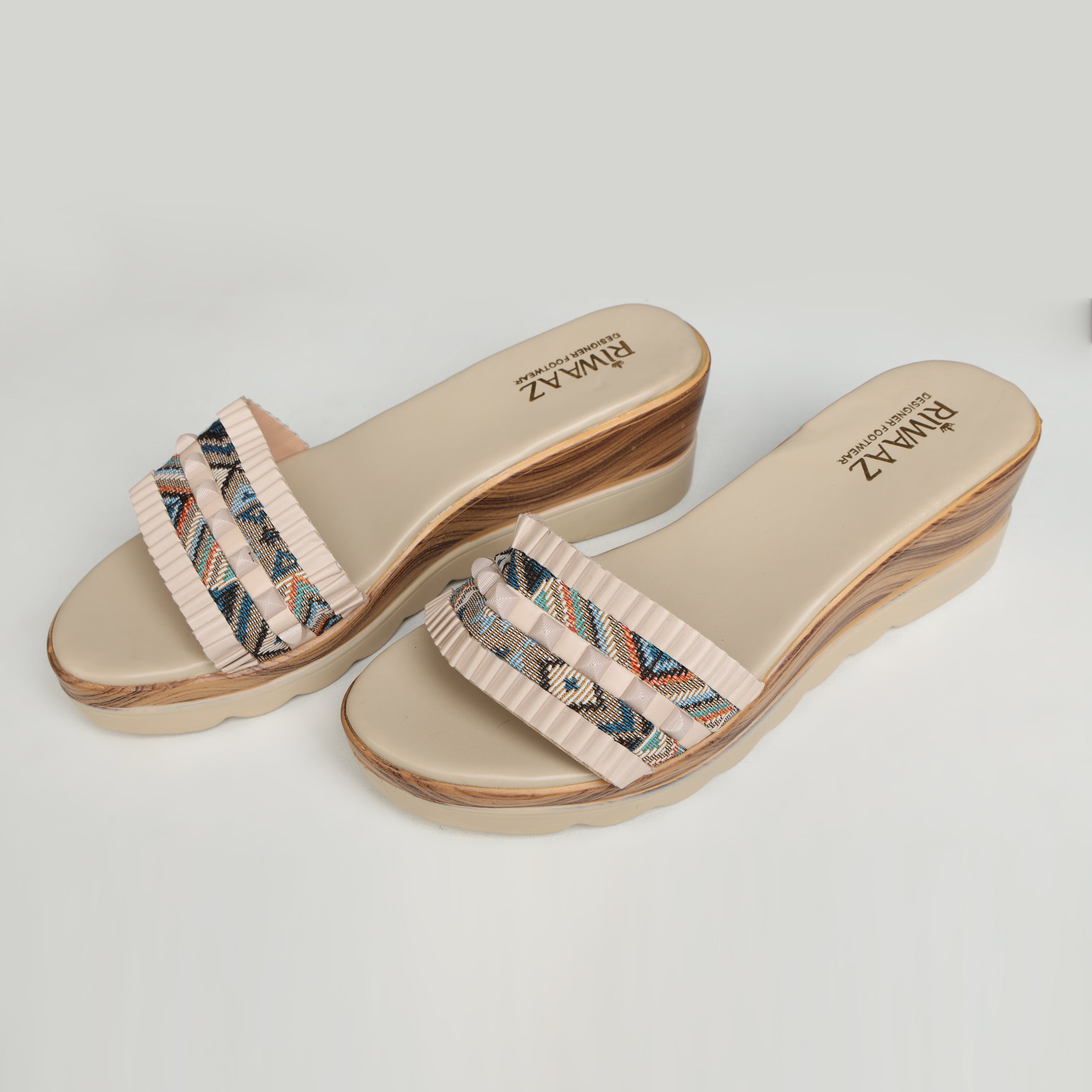 Single Riwaaz Elara cream printed pleated strap wedge slide – side profile product shot on white surface with grey fabric and Riwaaz box in background showing multicolour geometric print strap with cream pleated trim